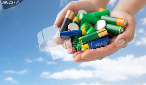 Image of close up of hands holding alkaline batteries heap