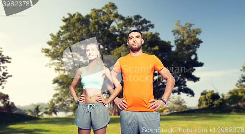 Image of happy couple exercising over summer park