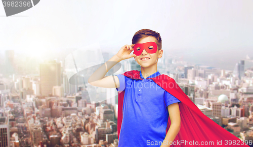 Image of boy in red superhero cape and mask over city