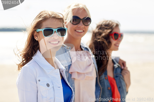Image of group of smiling women in sunglasses on beach
