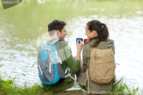 Image of happy couple with cups drinking in nature