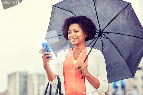 Image of businesswoman with umbrella texting on smartphone