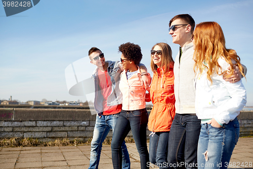 Image of happy teenage friends walking along city street