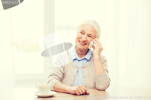 Image of senior woman with smartphone calling at home