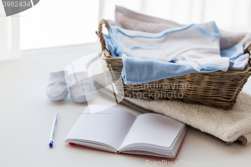 Image of close up of baby clothes for newborn and notebook