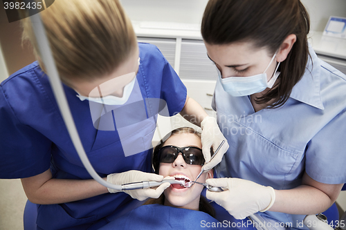 Image of female dentists treating patient girl teeth