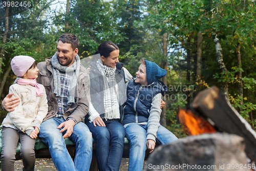 Image of happy family sitting on bench at camp fire