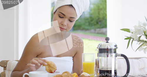 Image of Woman in towel dipping donut in coffee