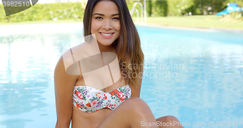 Image of Friendly happy young woman relaxing at the pool