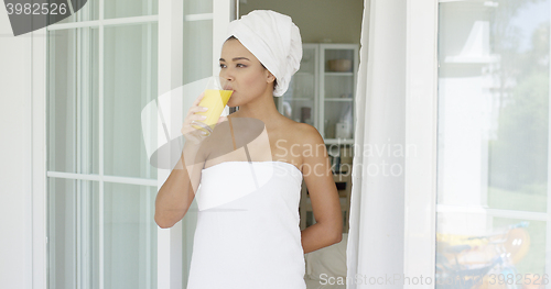 Image of Lady holding glass of juice while wrapped in towel