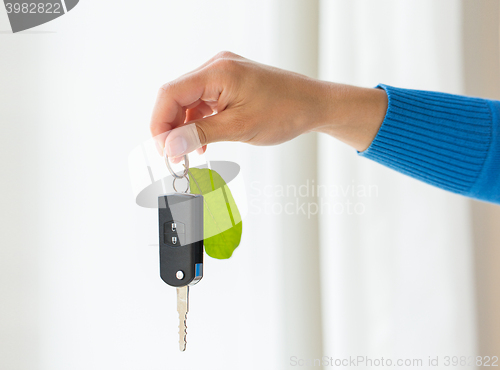 Image of close up of hand holding car key with green leaf