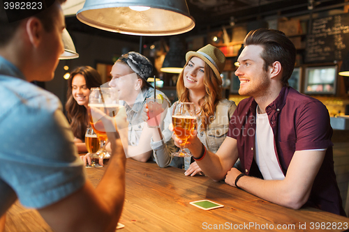 Image of happy friends with drinks talking at bar or pub