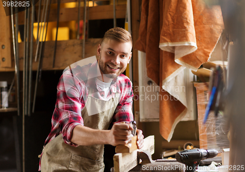 Image of carpenter working with plane and wood at workshop