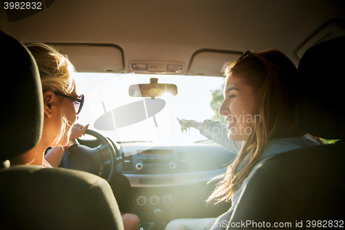 Image of happy teenage girls or women in car at seaside