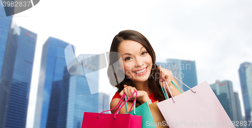 Image of happy woman with shopping bags over singapore city