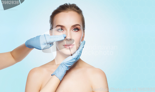 Image of surgeon or beautician hands touching woman face