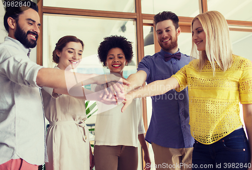 Image of happy creative team ith hands on top in office