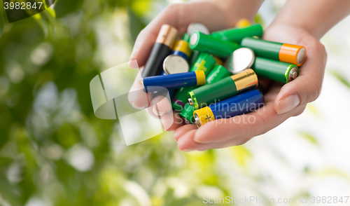 Image of close up of hands holding alkaline batteries heap