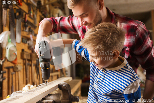 Image of father and son with drill working at workshop