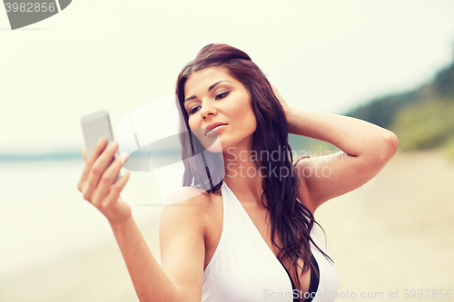 Image of young woman taking selfie with smartphone