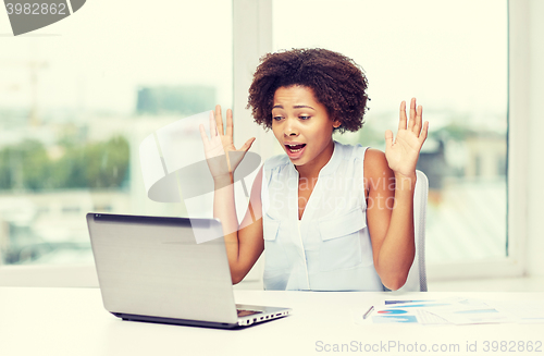Image of african woman with laptop at office