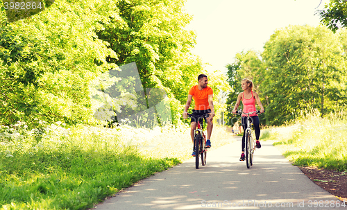 Image of happy couple riding bicycle outdoors