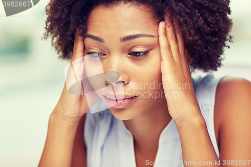 Image of close up of african young woman touching her head