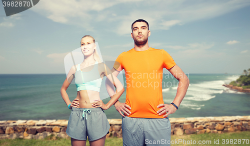 Image of happy couple exercising over sea or beach