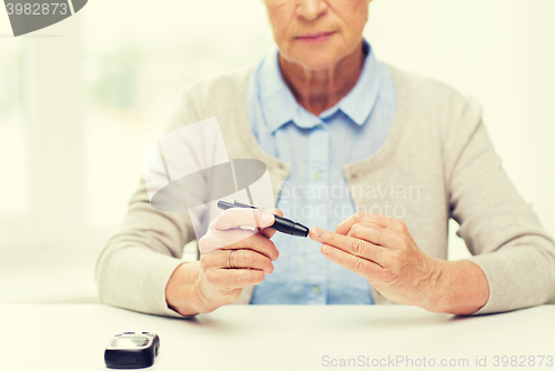 Image of senior woman with glucometer checking blood sugar