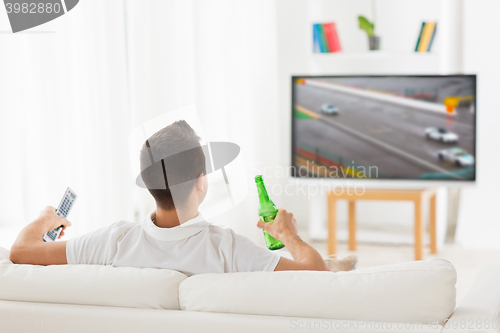 Image of man watching tv and drinking beer at home