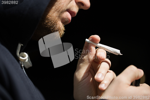 Image of close up of addict lighting up marijuana joint