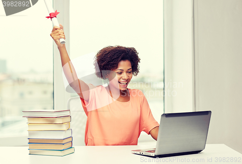 Image of happy african woman with laptop, books and diploma