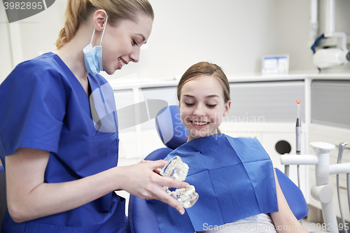 Image of happy dentist showing jaw model to patient girl
