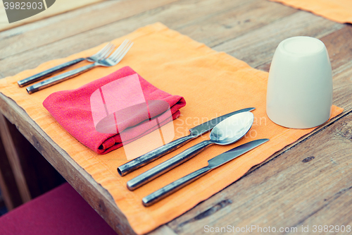 Image of close up of cutlery with glass and napkin on table