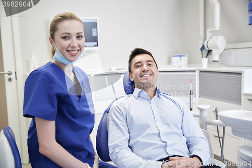 Image of happy female dentist with man patient at clinic