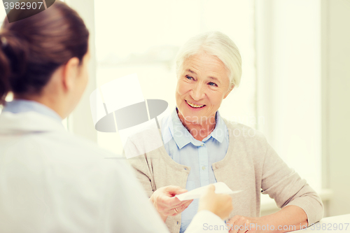 Image of doctor giving prescription to senior woman