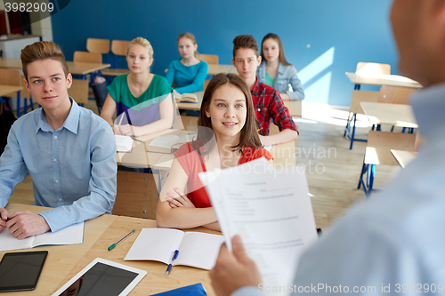 Image of group of students and teacher with papers or tests