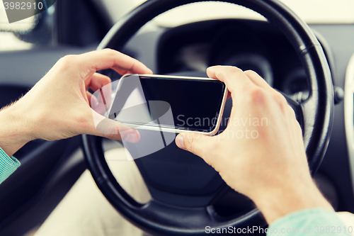 Image of close up of man hand with smartphone driving car