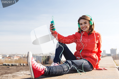 Image of happy young woman with smartphone and headphones