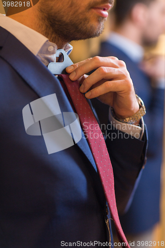 Image of close up of man trying tie on at clothing store