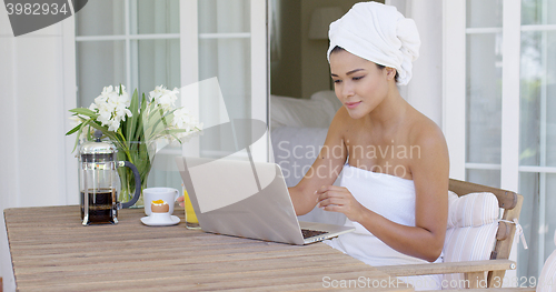 Image of Beautiful woman in bath towel using laptop