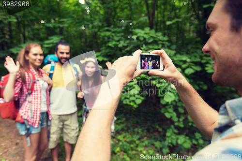 Image of happy man photographing friends by smartphone