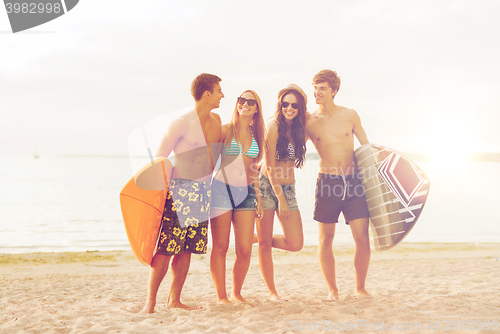 Image of smiling friends in sunglasses with surfs on beach