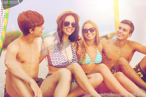 Image of smiling friends in sunglasses with surfs on beach