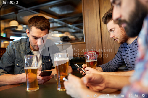 Image of men with smartphones drinking beer at bar or pub