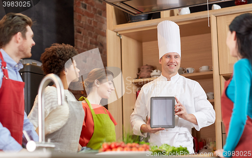 Image of happy friends with tablet pc in kitchen