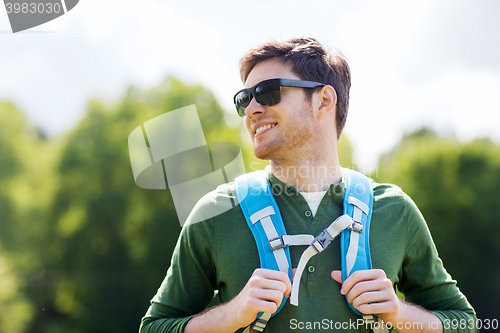 Image of happy young man with backpack hiking outdoors