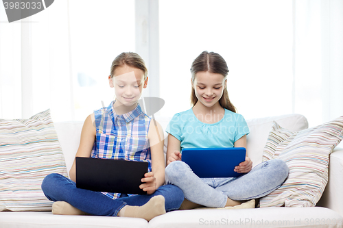 Image of happy girls with tablet pc sitting on sofa at home