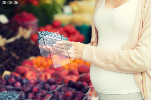 Image of pregnant woman buying blueberries at street market