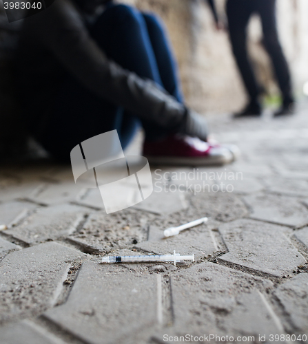 Image of close up of addicts and drug syringes on ground